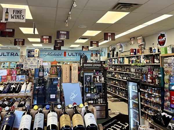 The spirits section with a Bourbon Legends display case and overhead signs for tequila, gin, vodka and liqueur.