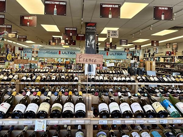 Rows of white wine bottles on wooden shelves beneath a handwritten card reading France.